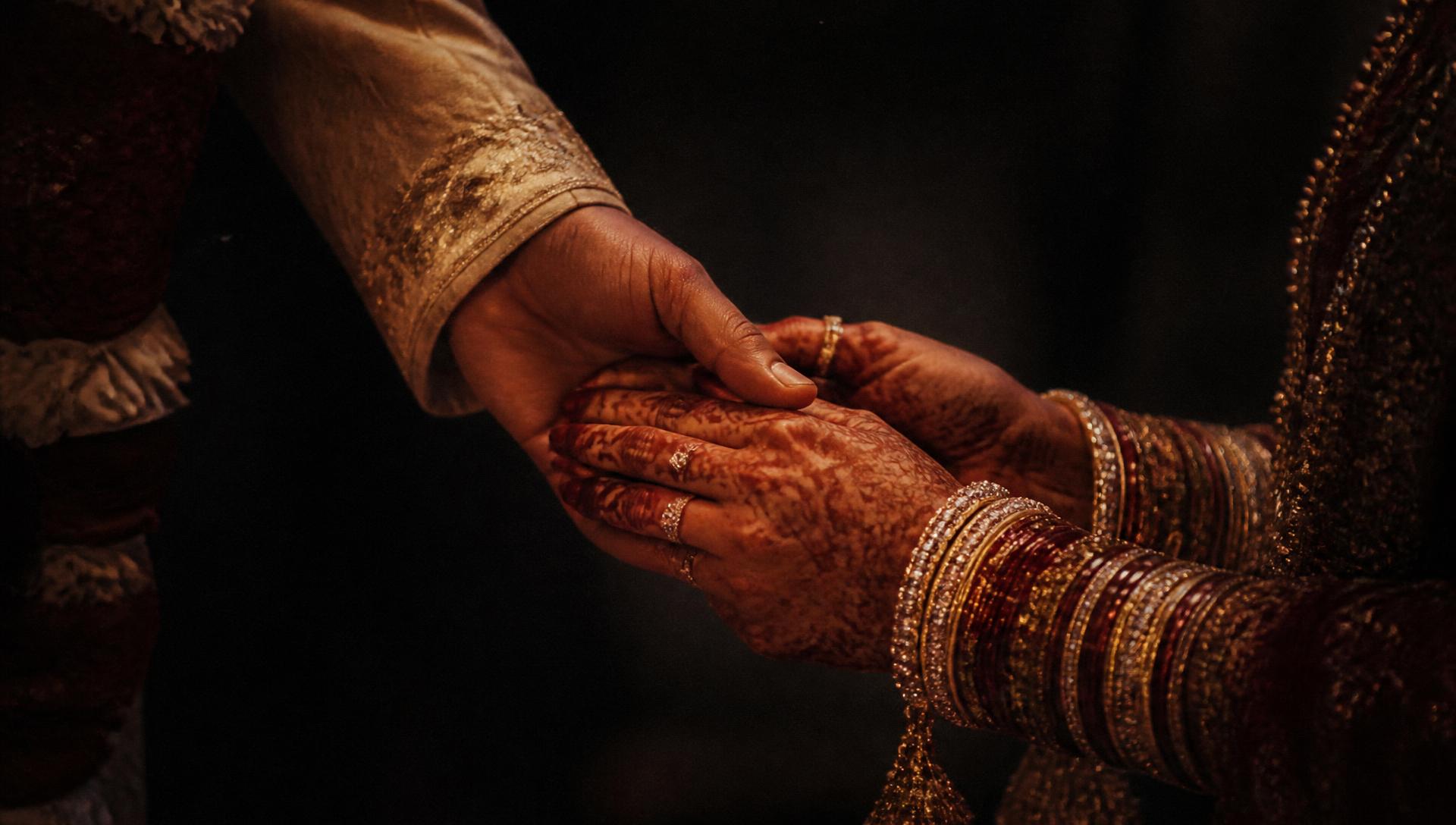 Close-up of a couple's hands with bridal mehendi and bangles